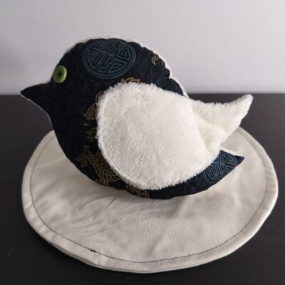 Peluche oiseau style japonais en tissu noir et doré avec une aile en éponge blanche et un œil bouton vert.