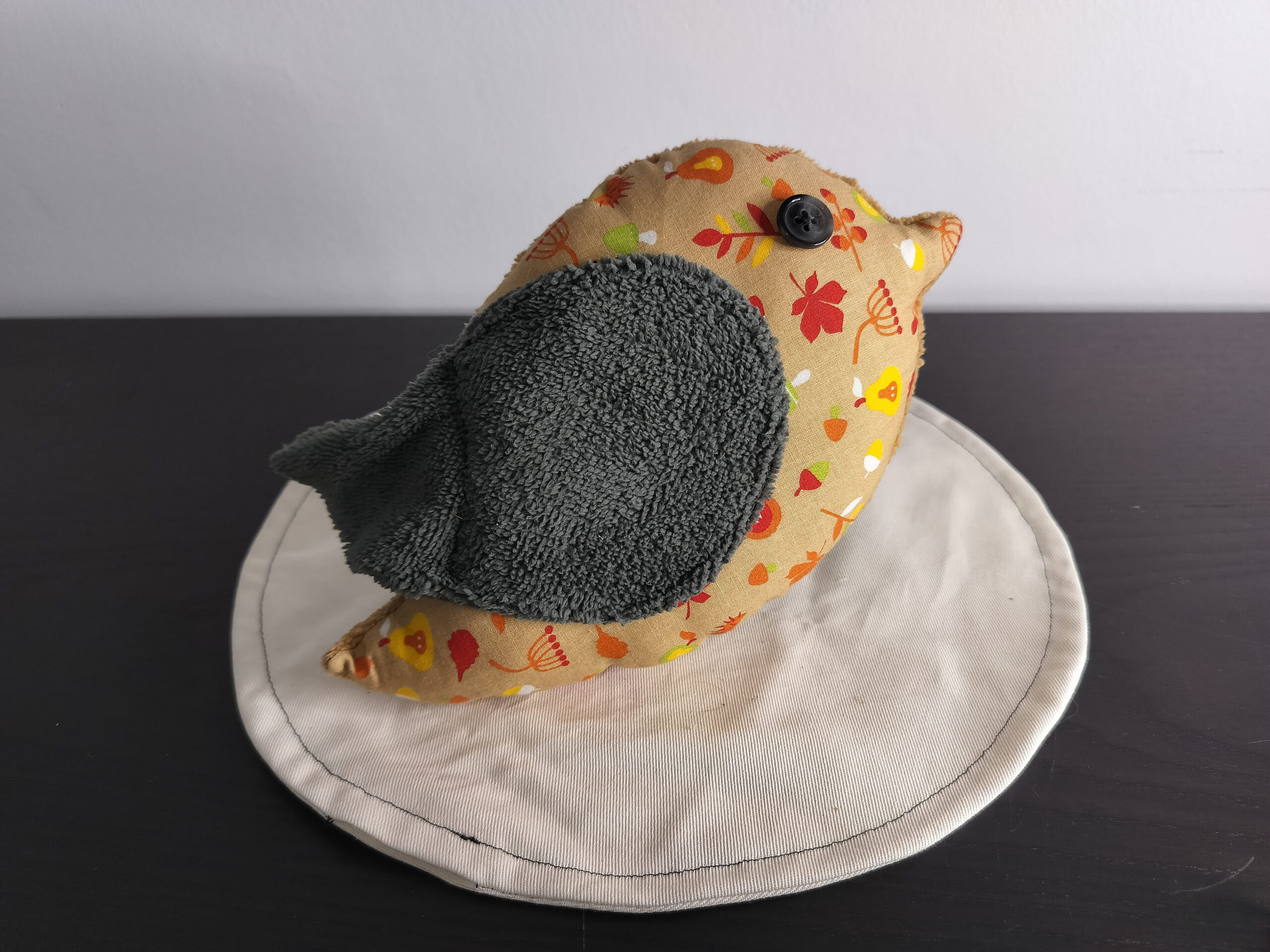Peluche oiseau aux motifs d'automne avec une aile gris anthracite en éponge et un œil bouton noir.