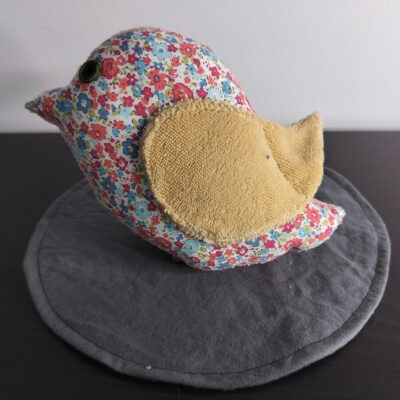 Peluche oiseau liberty en tissu fleuri avec une aile en éponge beige et un œil bouton vert.