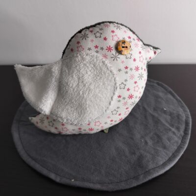 Peluche oiseau à motifs de petites fleurs avec une aile en éponge blanche et un œil bouton fantaisie.
