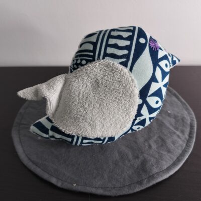 Oiseau décoratif en tissu wax bleu avec une aile en éponge gris clair et une broderie violette.