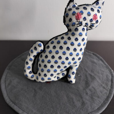 Peluche chat blanc creme a petits motifs geometriques bleu azur et marine yeux etoiles brodees rose fuchsia envers eponge noire fait main
