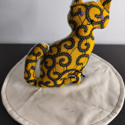 Peluche chat jaune de la collection Cameroun a motifs spirales noires et blanches yeux etoiles brodes violets envers eponge creme