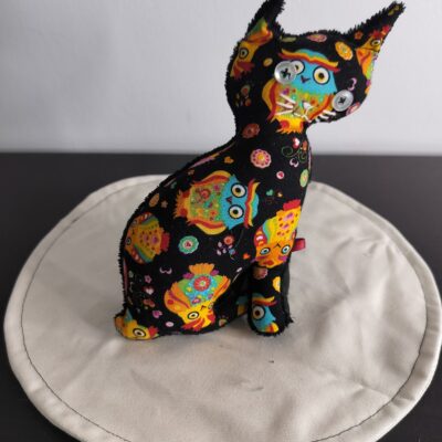Peluche chat noir gamme Handi-peluche sans queue a motifs de hiboux et chouettes psychedeliques multicolores grands yeux boutons clairs envers eponge noire fait main