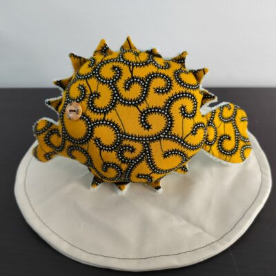 Peluche poisson globe Cameroun fait main en tissu jaune moutarde a motifs de volutes noires et blanches oeil bouton marron et texture peluche blanche