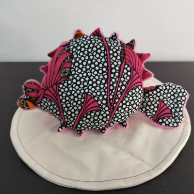 Peluche poisson globe Cameroun fait main en tissu rose fuchsia a motifs de cercles noirs et blancs oeil bouton noir et pointes orange avec texture peluche rose