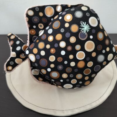 Peluche poisson rond artisanale en tissu noir a motifs confettis multicouleurs oeil etoile brode vert deau et dessous en eponge rose pale