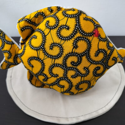 Peluche poisson rond de la collection Cameroun en tissu Wax jaune à motifs spirales avec un œil étoile rouge brodé main.