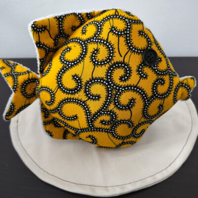 Peluche poisson rond de la collection Cameroun en tissu Wax jaune à motifs spirales avec un œil bouton noir classique.