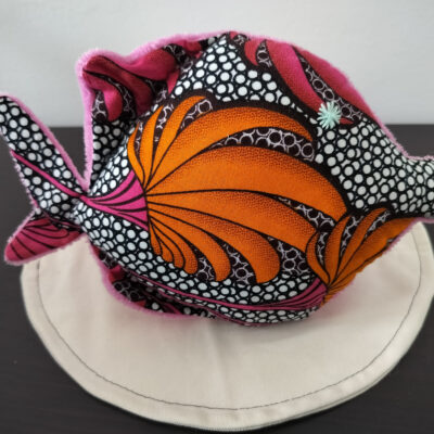 Peluche poisson rond de la collection Cameroun en tissu Wax rose fuchsia et orange avec un œil étoile vert d'eau brodé main.