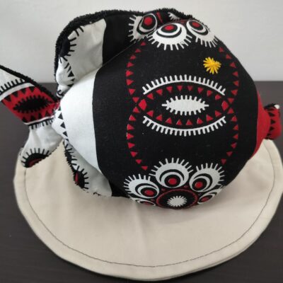 Peluche poisson rond de la collection Guyane en tissu ethnique noir, blanc et rouge avec un œil étoile jaune brodé main.