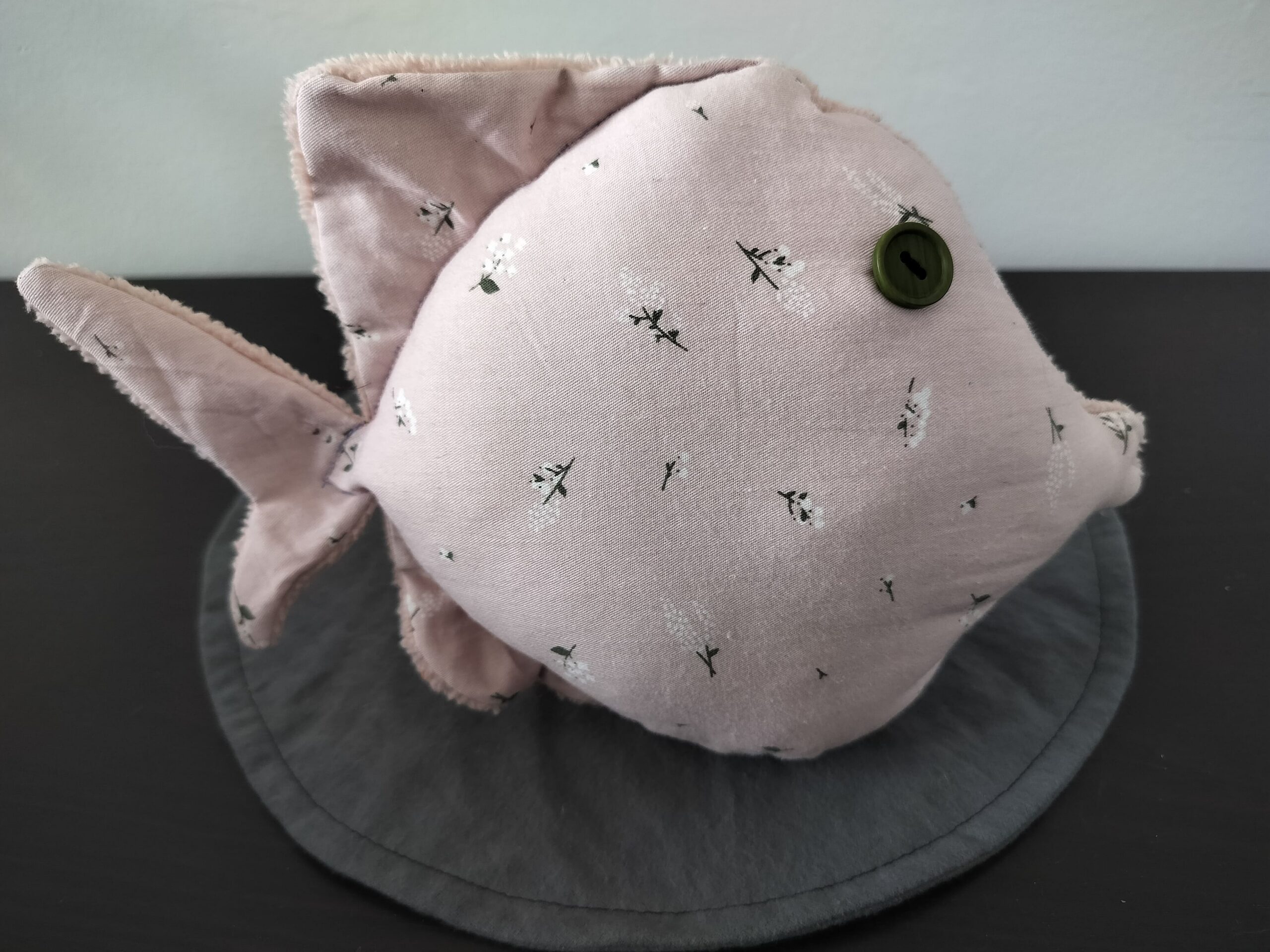 Peluche poisson rond au tissu vieux rose à motifs de brins de muguet avec un œil bouton vert olive.
