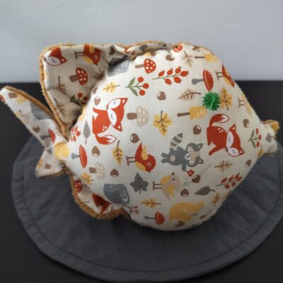 Peluche poisson rond au tissu beige imprimé d'animaux de la forêt et renards avec un œil étoile vert brodé main.