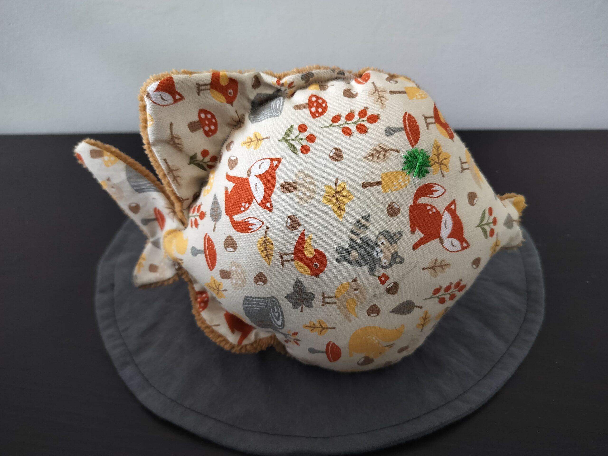 Peluche poisson rond au tissu beige imprimé d'animaux de la forêt et renards avec un œil étoile vert brodé main.
