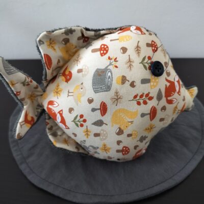 Peluche poisson rond au tissu beige imprimé d'animaux de la forêt et renards avec un œil bouton noir rétro.