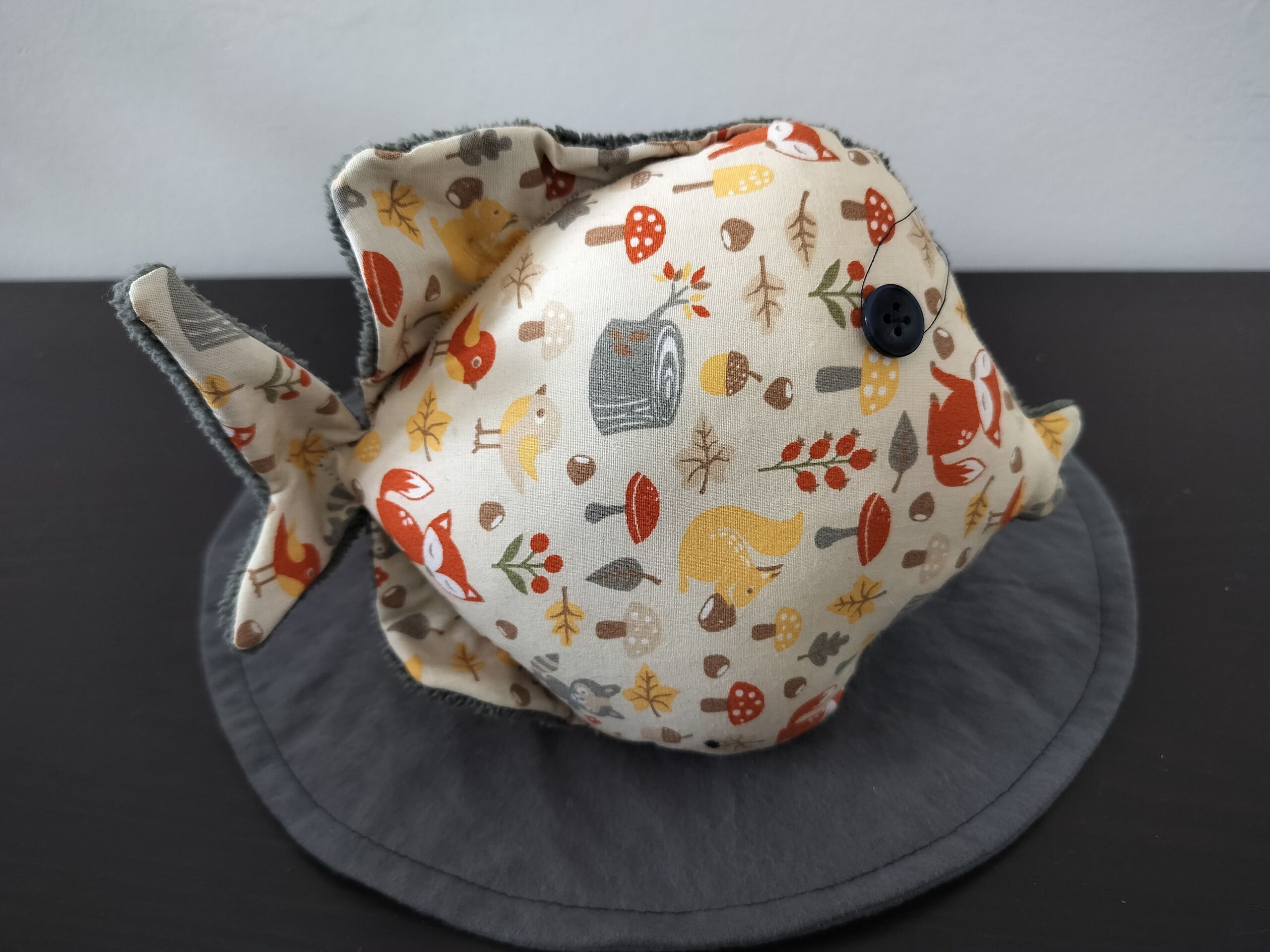 Peluche poisson rond au tissu beige imprimé d'animaux de la forêt et renards avec un œil bouton noir rétro.