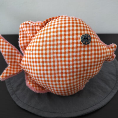 Peluche poisson rond au tissu à carreaux vichy orange et blanc avec un œil bouton en bois bleu marine fleuri.