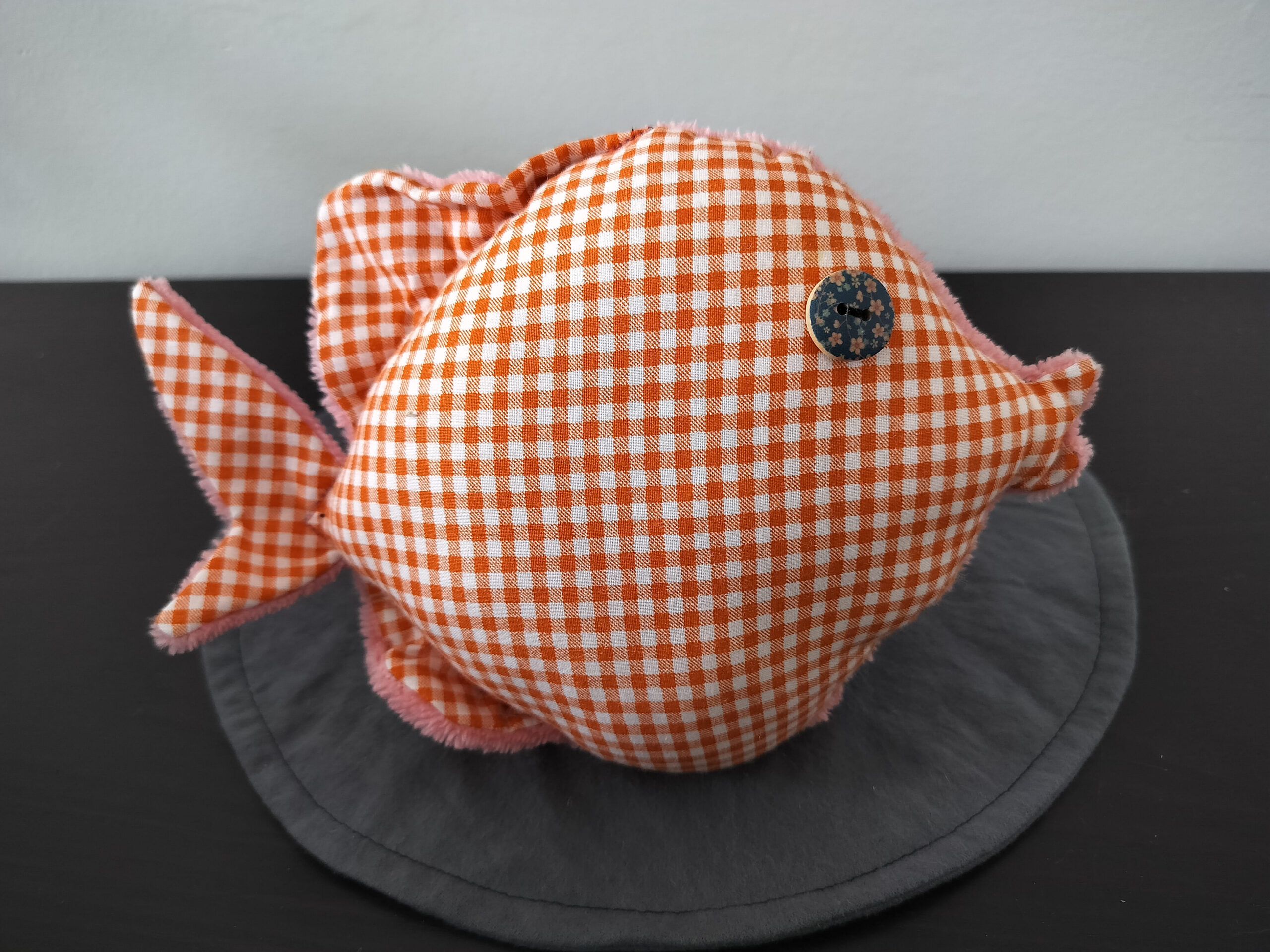 Peluche poisson rond au tissu à carreaux vichy orange et blanc avec un œil bouton en bois bleu marine fleuri.