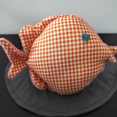 Peluche poisson rond au tissu à carreaux vichy orange et blanc avec un œil en forme d'étoile bleue brodé main.