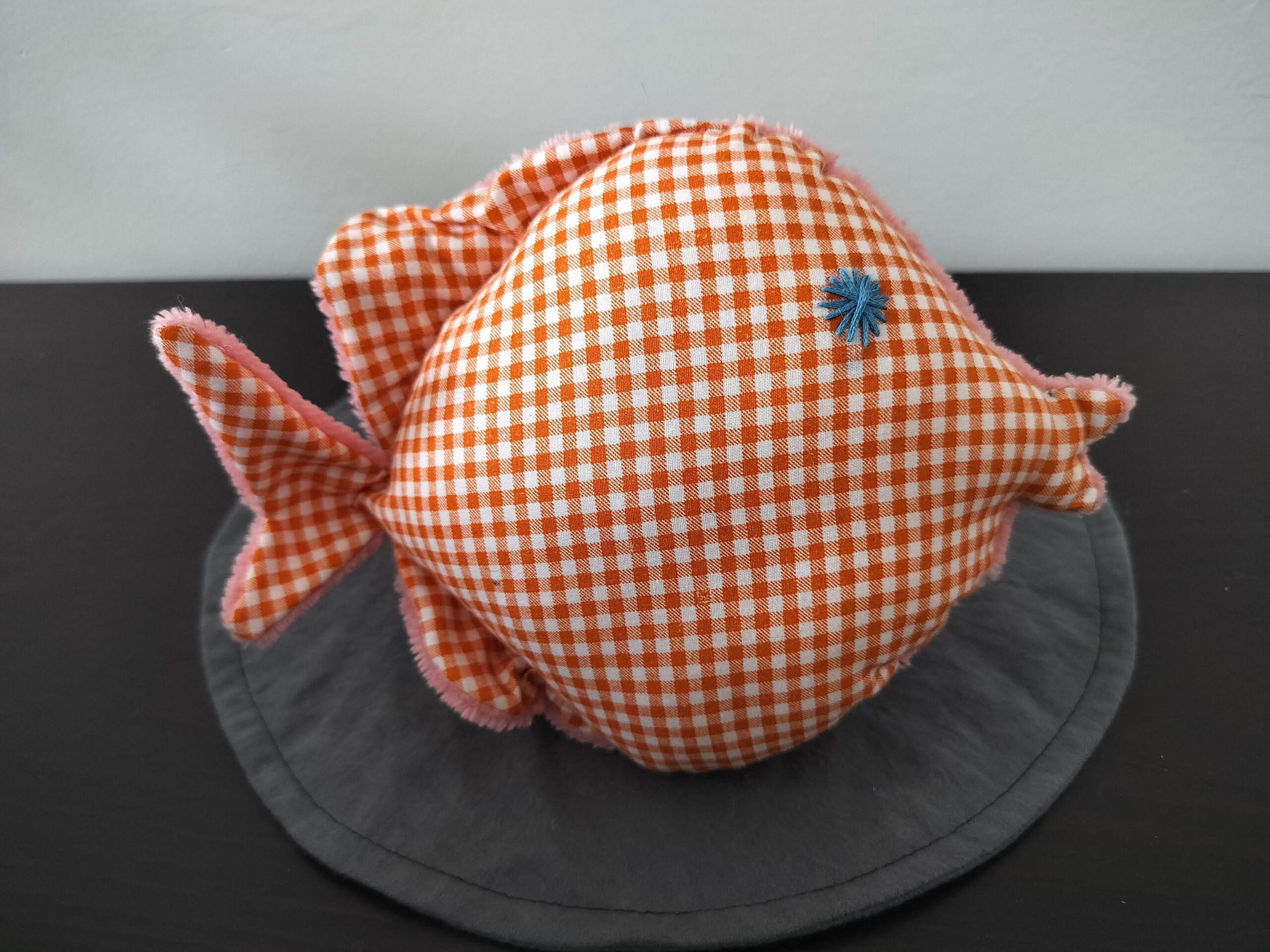Peluche poisson rond au tissu à carreaux vichy orange et blanc avec un œil en forme d'étoile bleue brodé main.