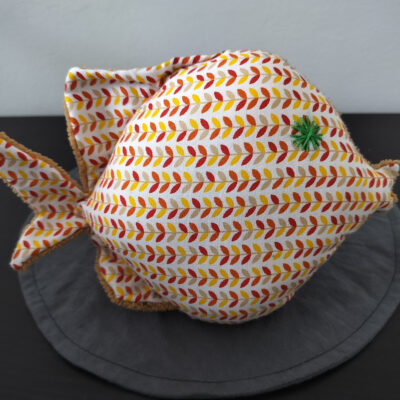 Peluche poisson rond au tissu blanc imprimé d'épis terracotta et jaune avec un œil en forme d'étoile vert sapin brodé main.