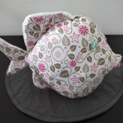 Peluche poisson rond au tissu fleuri blanc et rose avec un œil en forme d'étoile vert d'eau brodé à la main.