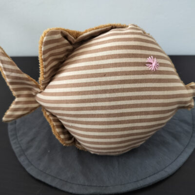 Peluche poisson rond rayé beige et blanc avec un œil en forme d'étoile rose brodé à la main, création artisanale.