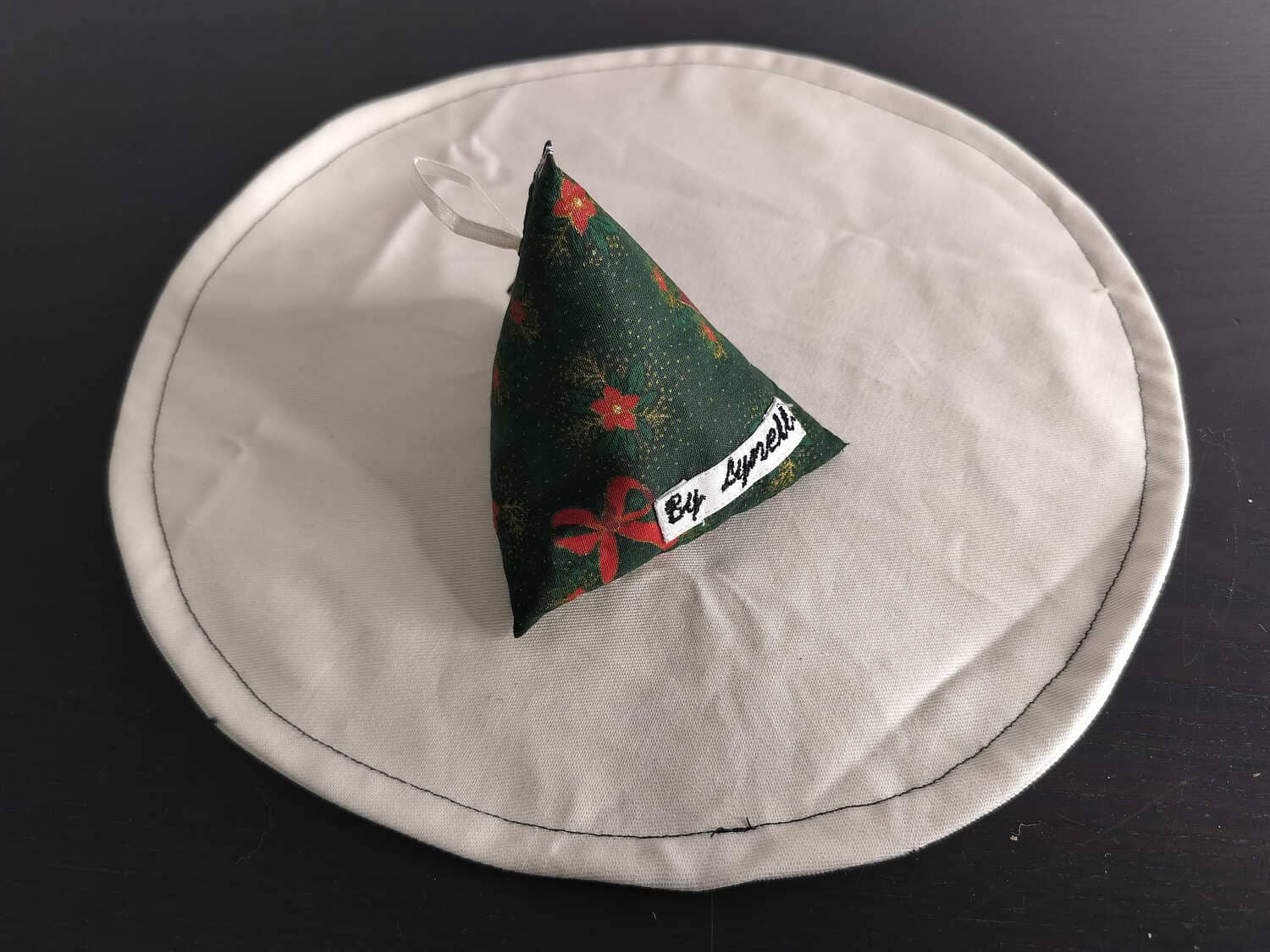 Bouillotte sèche Noël sapin et rouge, berlingot en tissu artisanal aux motifs de fêtes et de fleurs rouges.