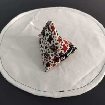 Bouillotte sèche étoiles de Noël, berlingot en tissu artisanal aux motifs d'étoiles dorées et cuivrées sur fond rouge et blanc.