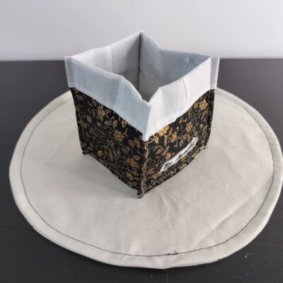 Vide-poche en tissu baroque et sophistiqué, petit panier carré bicolore avec revers blanc un tissu noir constellé de motifs floraux et de volutes dorées.