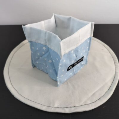 Vide-poche en tissu bleu pastel, petit panier carré bicolore avec revers blanc un coton bleu pastel poudré parsemé de petites étoiles blanches.