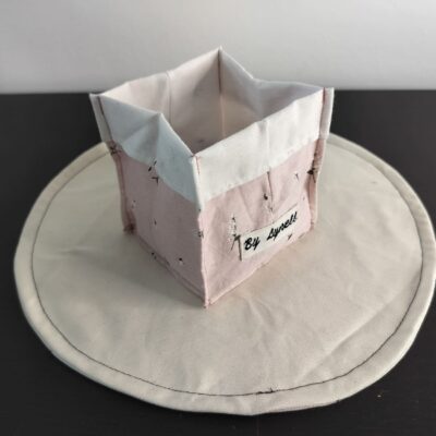 Vide-poche en tissu rose poudré, petit panier carré bicolore avec revers blanc en coton imprimé de délicates brindilles.