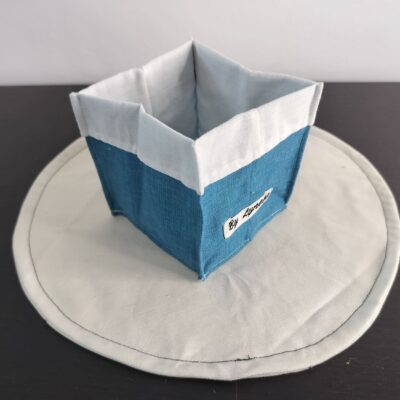 Vide-poche en tissu uni, petit panier carré bicolore avec revers blanc en coton bleu canard texturé.