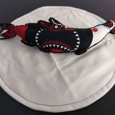 Peluche sardine aux motifs guyanais, avec yeux brodés rouge et tissu éponge noir.