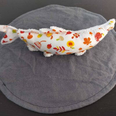 Peluche sardine feuillage d'automne fond clair, avec yeux brodés saumon et tissu éponge blanc.